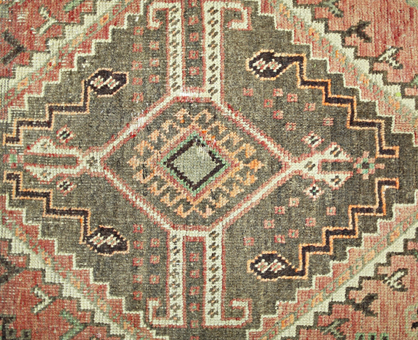 A vintage Persian Shiraz rug featuring a geometric diamond medallion in brown, red, and cream.