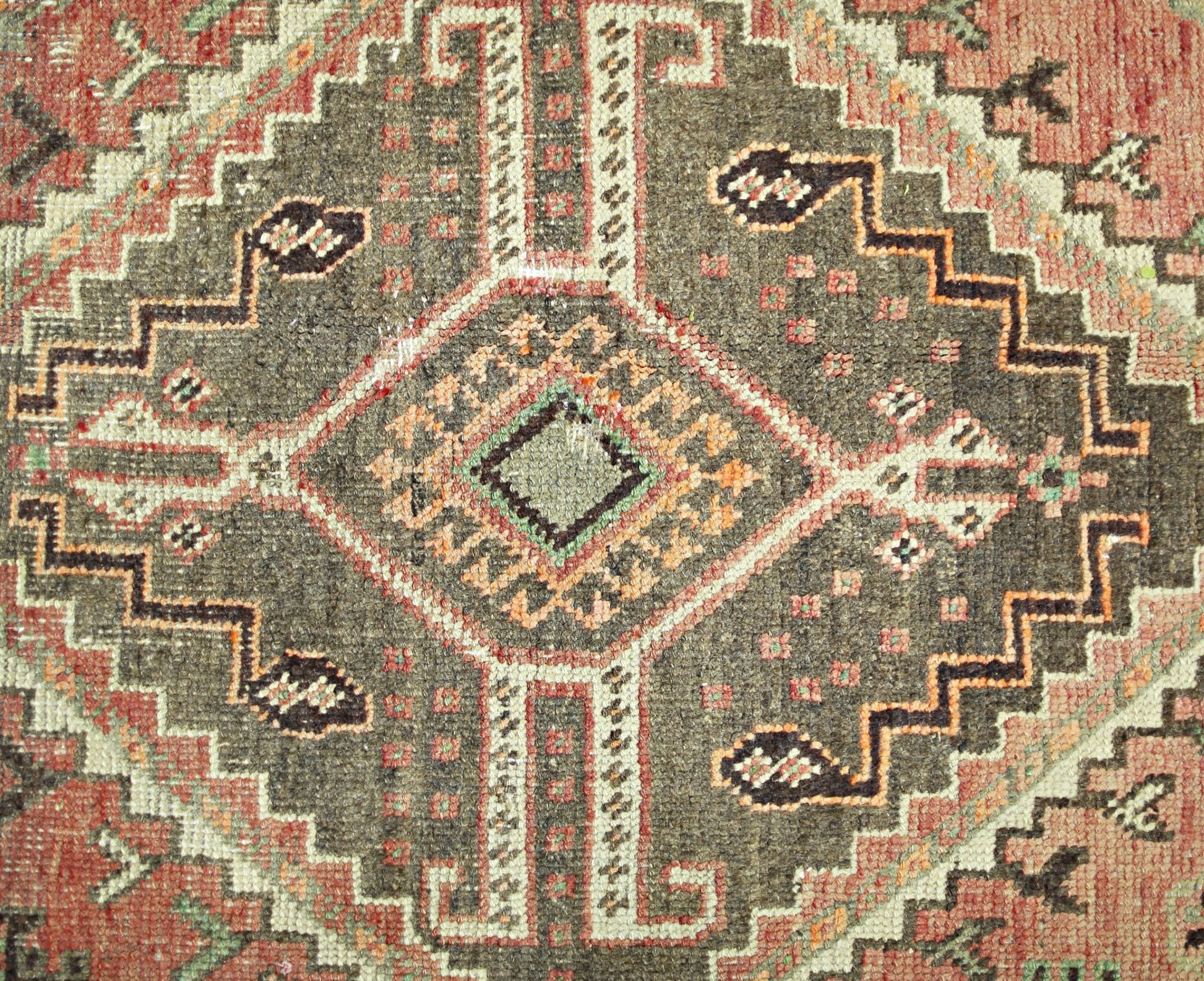 A vintage Persian Shiraz rug featuring a geometric diamond medallion in brown, red, and cream.