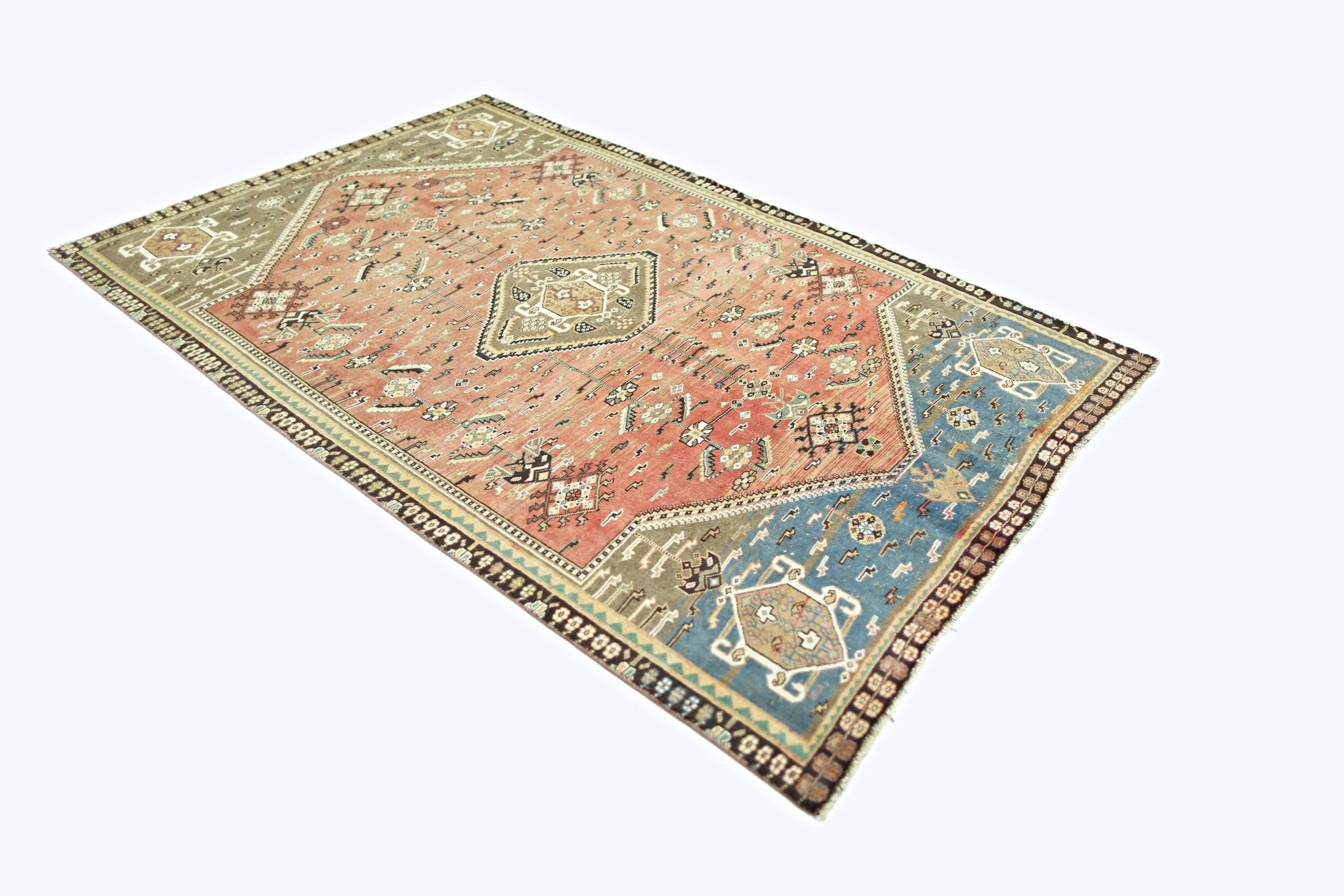 A vintage Persian Shiraz rug featuring a geometric medallion design in red, blue, and tan wool.