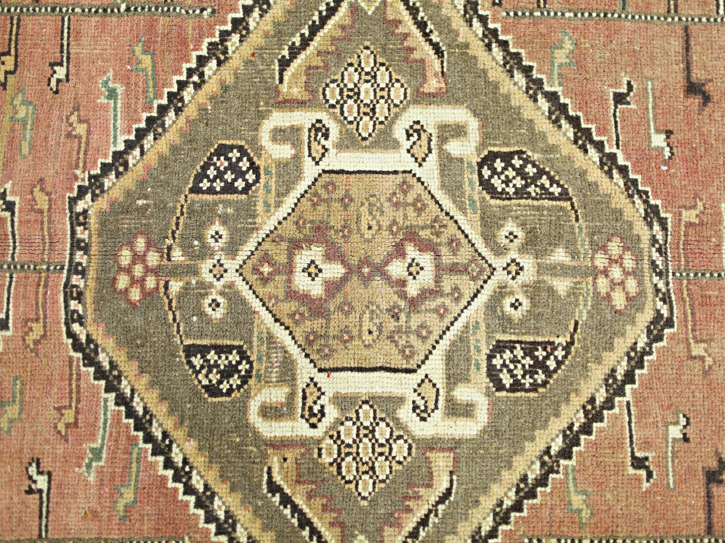 A vintage Persian Shiraz rug featuring a central geometric medallion in olive and terracotta tones.