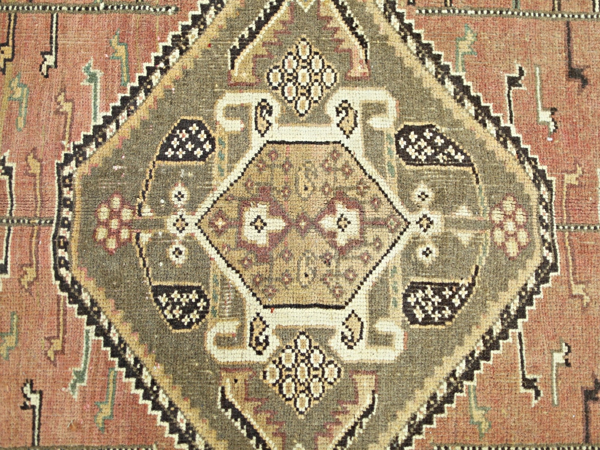 A vintage Persian Shiraz rug featuring a central geometric medallion in olive and terracotta tones.