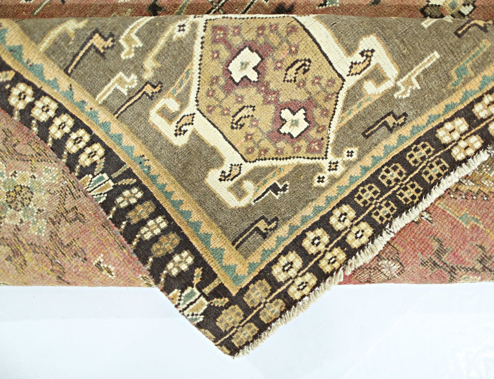 A folded vintage Persian Shiraz rug featuring a geometric medallion pattern in earthy tones.