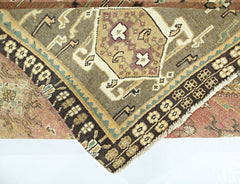 A folded vintage Persian Shiraz rug featuring a geometric medallion pattern in earthy tones.