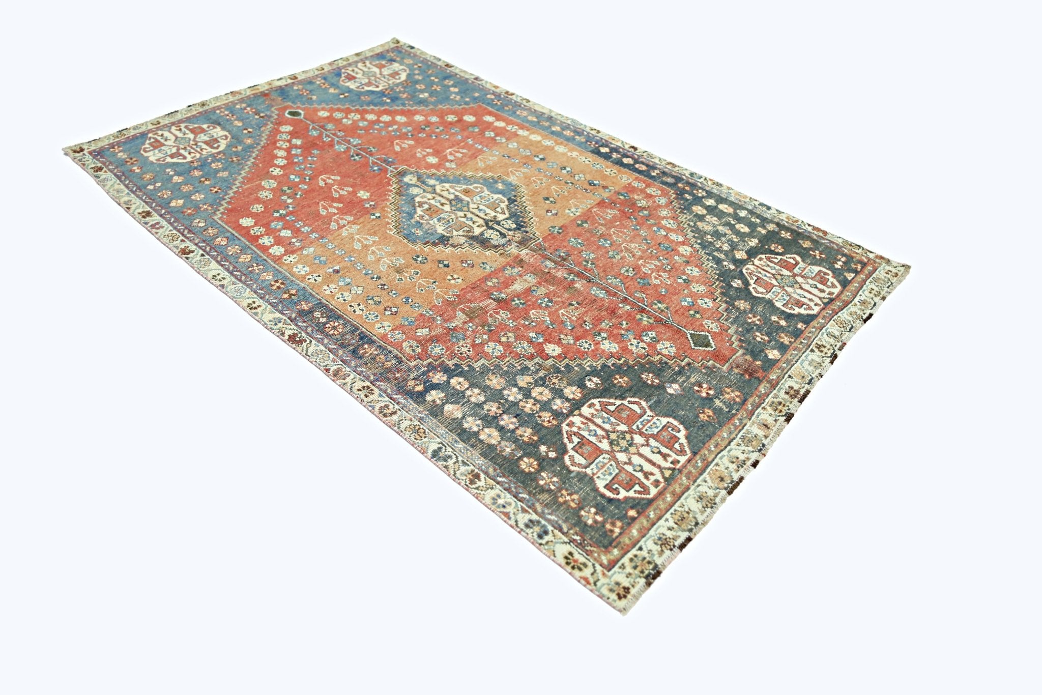 A vintage Persian Shiraz rug featuring a geometric medallion on a red and blue field.