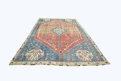 A vintage Persian Shiraz rug featuring a central diamond medallion on a red and blue field.