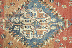 A vintage Persian Shiraz rug featuring a central blue diamond medallion on a red field.