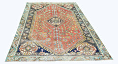 A vintage handmade Persian Shiraz rug featuring a geometric red field with blue and cream accents.