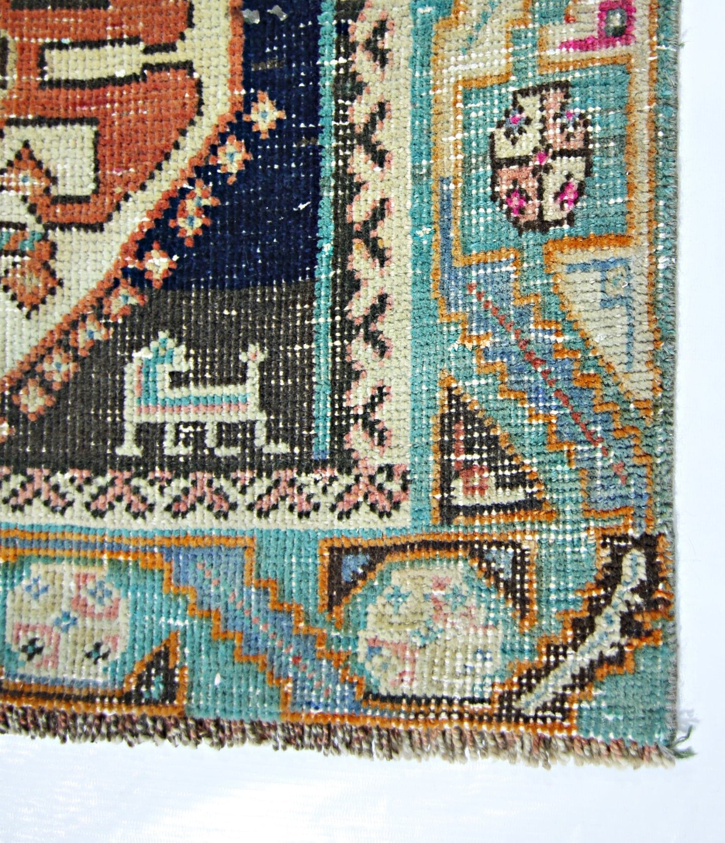 A close-up of a vintage Persian Shiraz rug featuring intricate geometric patterns in blue, orange, and cream.