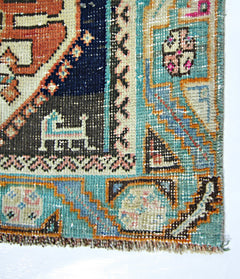 A close-up of a vintage Persian Shiraz rug featuring intricate geometric patterns in blue, orange, and cream.