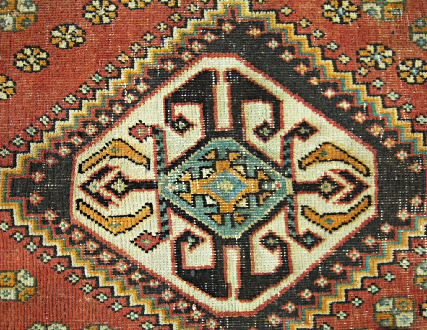 A vintage Persian Shiraz rug featuring a central geometric diamond medallion on a red field.
