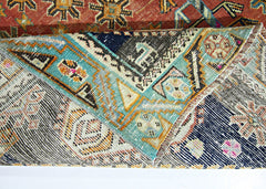 A folded vintage Persian Shiraz rug featuring intricate geometric patterns in blue, red, and cream.