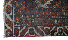 A vintage Persian Shiraz rug featuring intricate geometric patterns in deep blue and rust red.