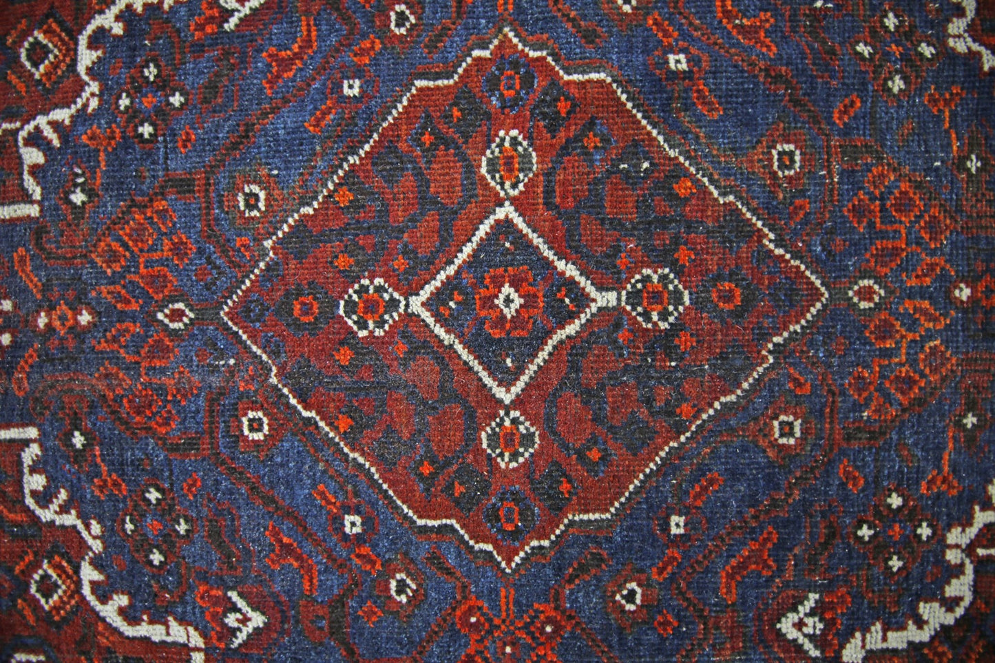 A vintage Persian Shiraz rug featuring a central diamond medallion in red and blue wool.