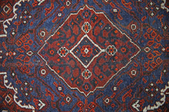 A vintage Persian Shiraz rug featuring a central diamond medallion in red and blue wool.