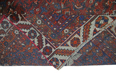 A corner of a vintage Persian Shiraz rug with a geometric pattern in red, blue, and cream.