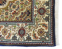 A vintage Persian silk Tabriz rug featuring intricate floral patterns in cream, blue, and red.