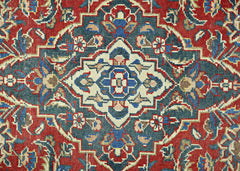 A vintage Persian rug featuring a central geometric medallion in blue, cream, and red tones.