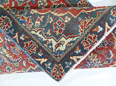A folded vintage Persian rug featuring intricate floral patterns in red, blue, and cream tones.