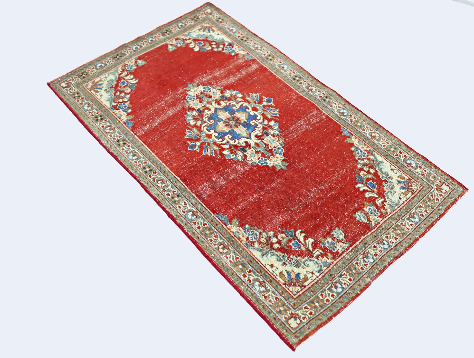 A vintage handmade Persian Tabriz rug featuring a central floral medallion on a red field.