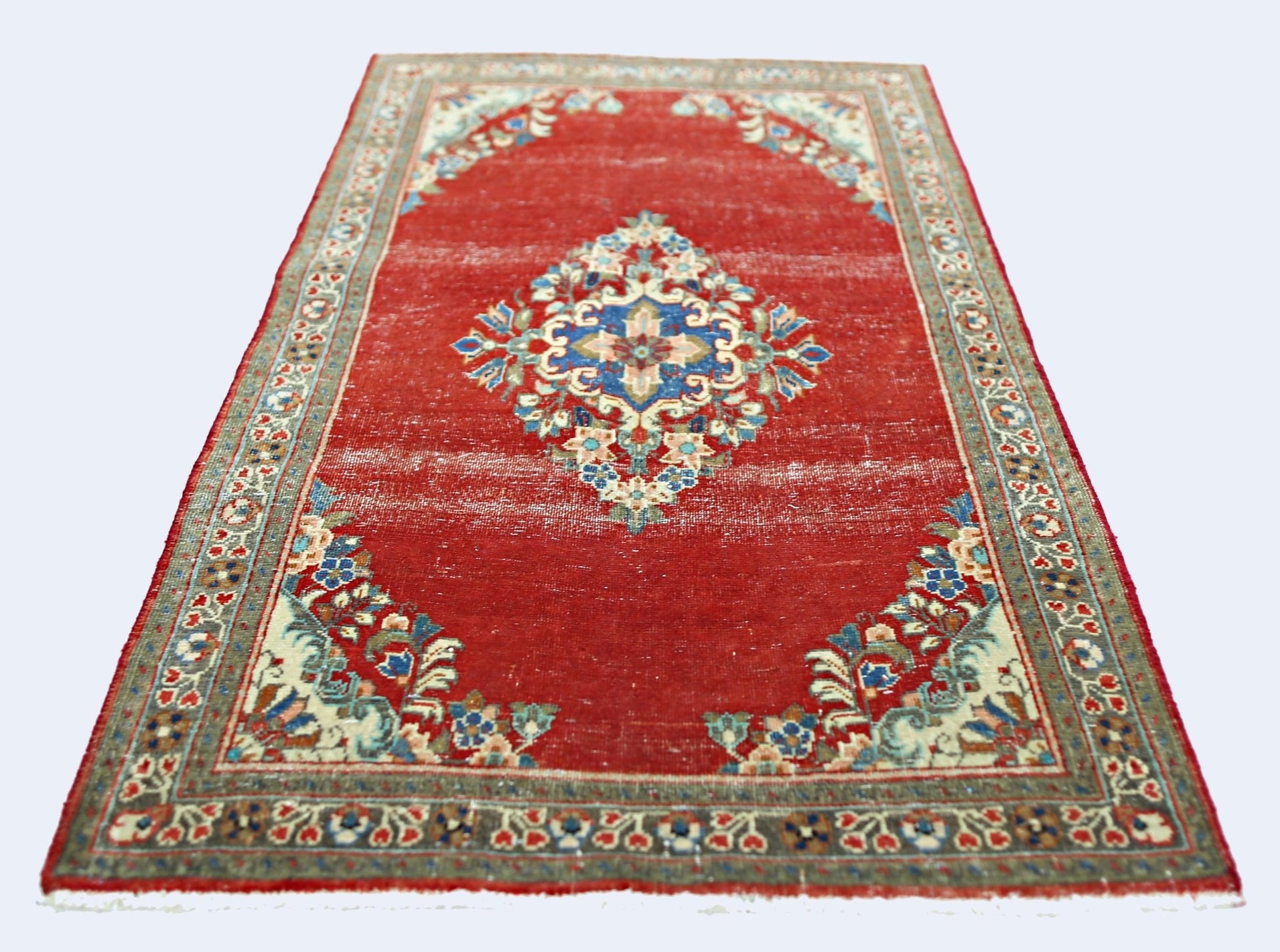 A vintage handmade Persian Tabriz rug featuring a central floral medallion on a red field.