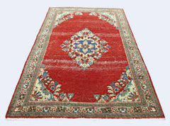 A vintage handmade Persian Tabriz rug featuring a central floral medallion on a red field.