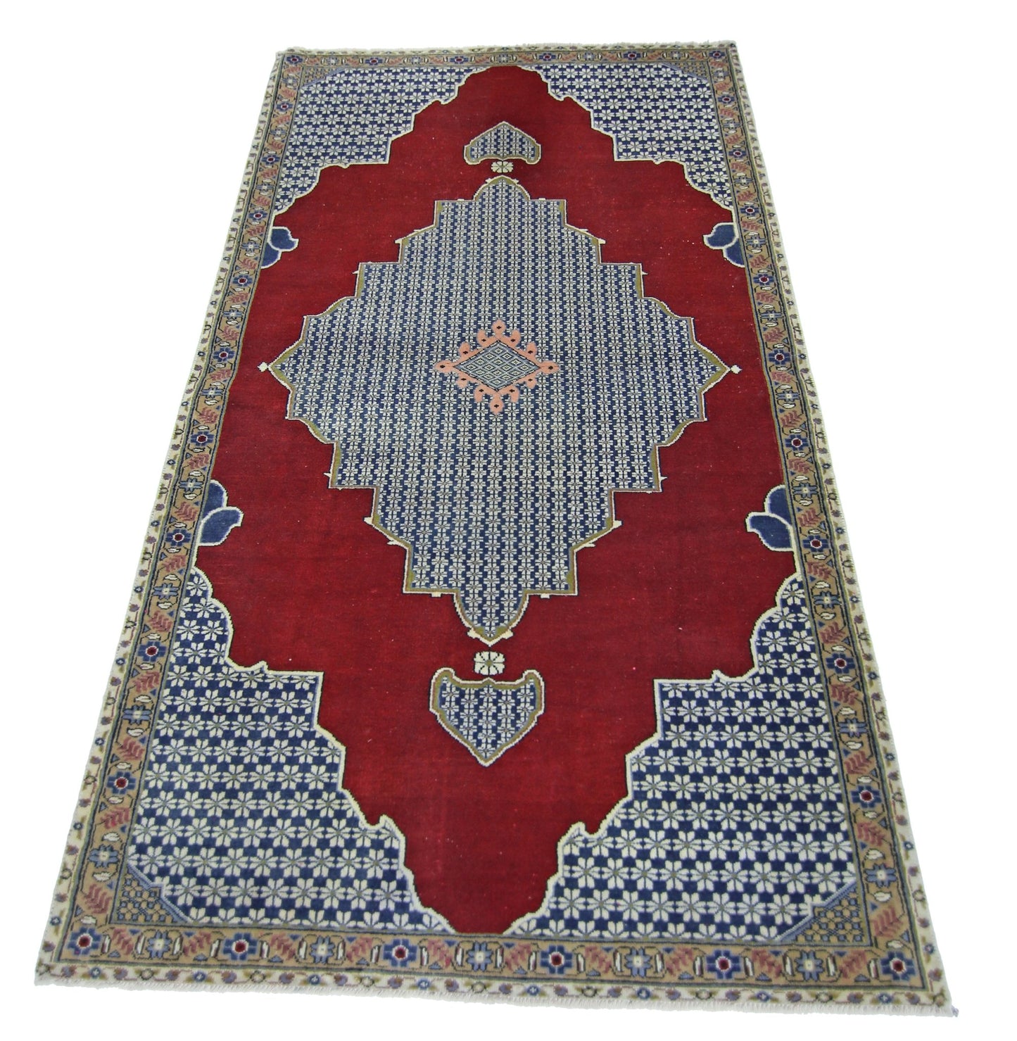 A vintage handmade Persian rug featuring a red field with a blue geometric medallion and floral border.