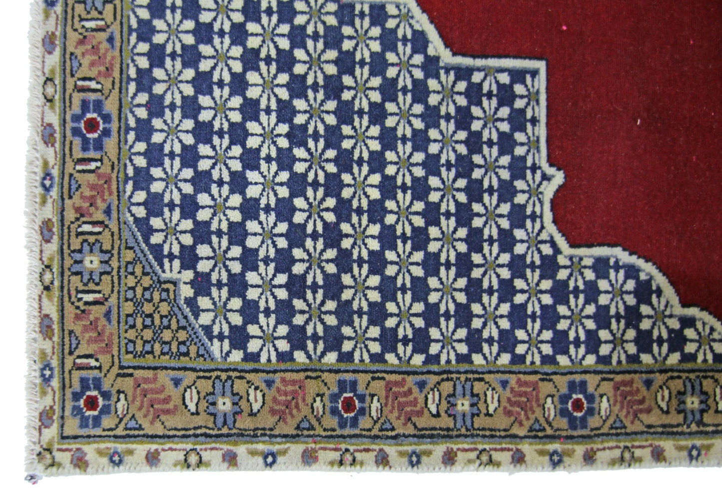 A vintage Persian rug featuring a blue field with white floral patterns and a red corner section.