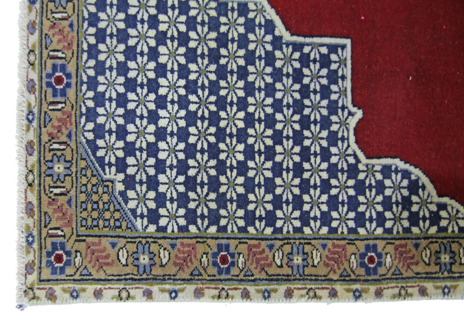 A vintage Persian rug featuring a blue field with white floral patterns and a red corner section.
