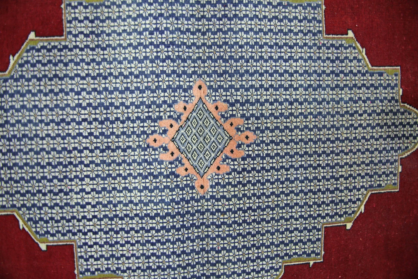 A vintage Persian rug featuring a blue field with a repeating floral pattern and a central diamond.