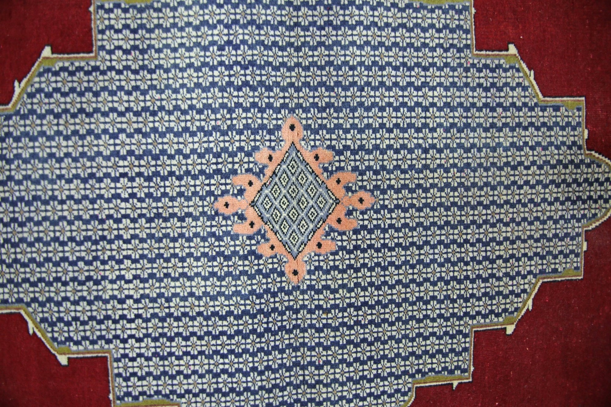A vintage Persian rug featuring a blue field with a repeating floral pattern and a central diamond.