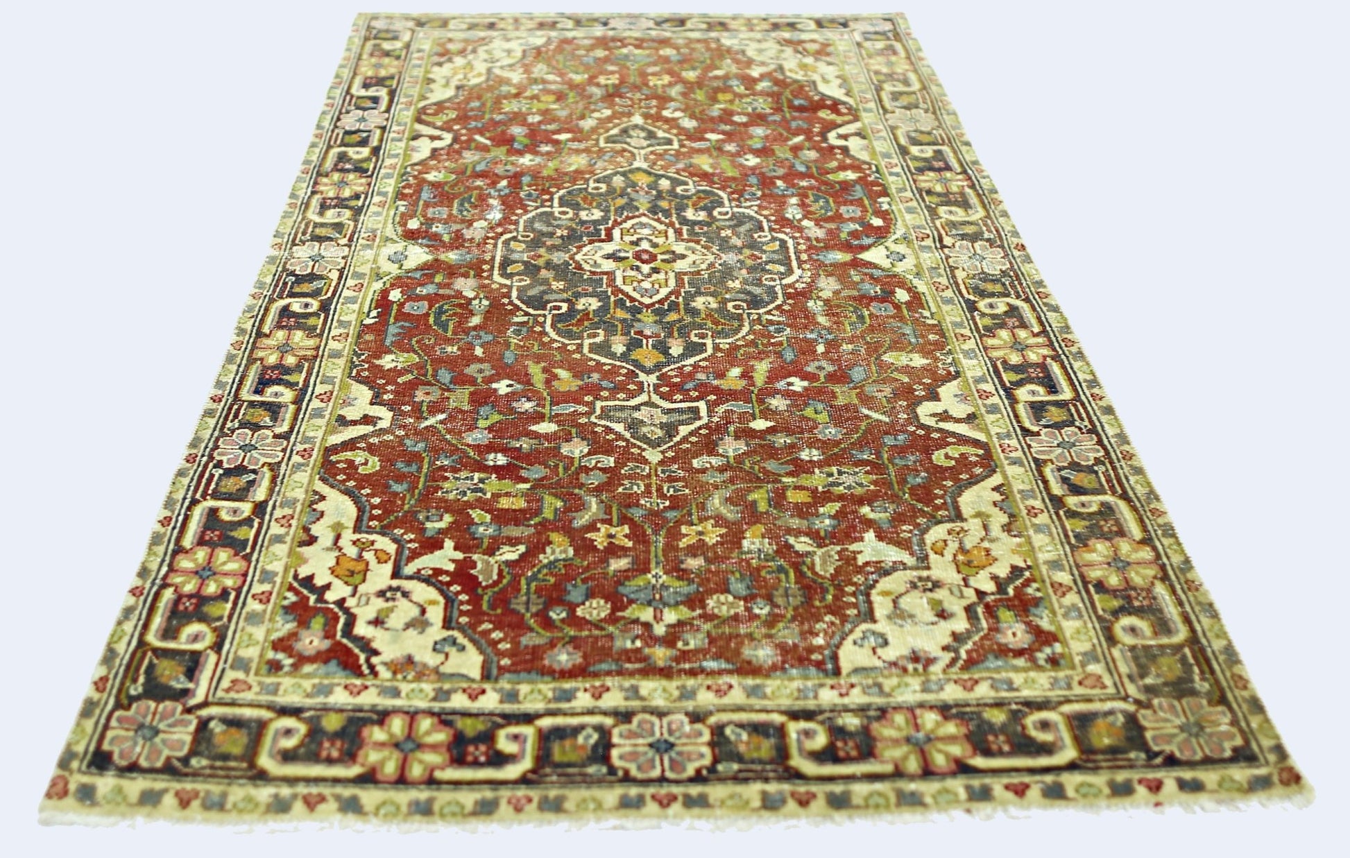 A rectangular vintage Persian rug featuring a central medallion on a red field with floral patterns.