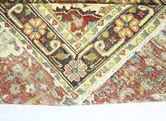 A folded vintage Persian rug featuring intricate floral patterns in red, blue, and cream tones.