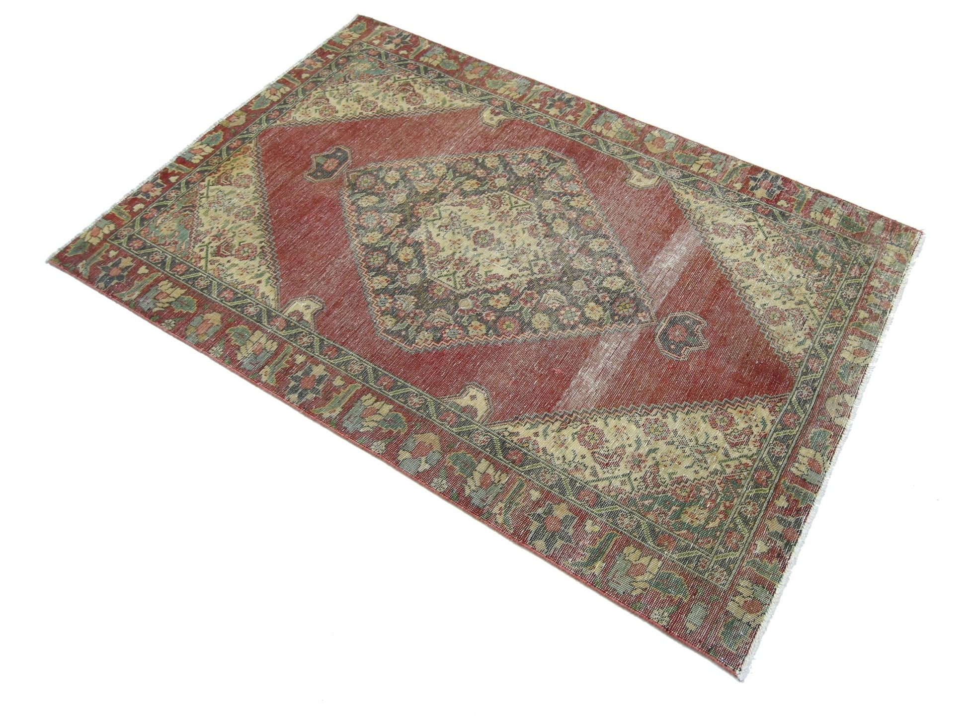 A vintage handmade Persian rug featuring a central medallion on a red field with floral borders.