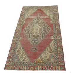A vintage handmade Persian rug featuring a central diamond medallion on a red field.