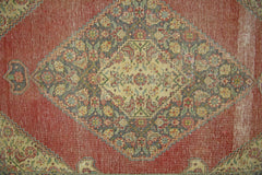 A vintage Persian rug featuring a central diamond medallion with intricate floral patterns.