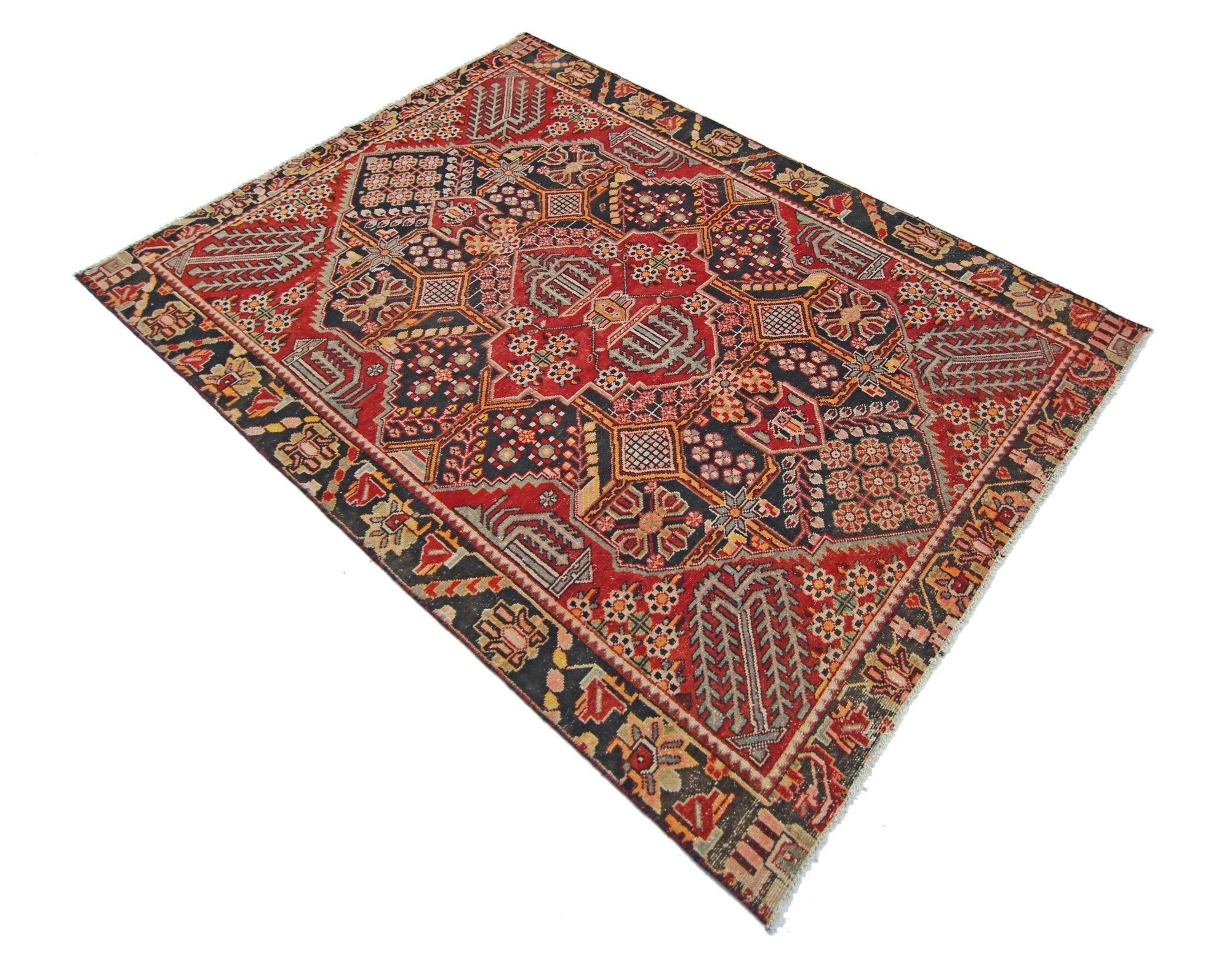 A vintage Persian Tabriz rug featuring intricate geometric patterns in red, black, and cream tones.