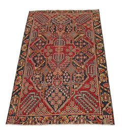 A vintage Persian Tabriz rug featuring a geometric floral pattern in red, black, and cream tones.