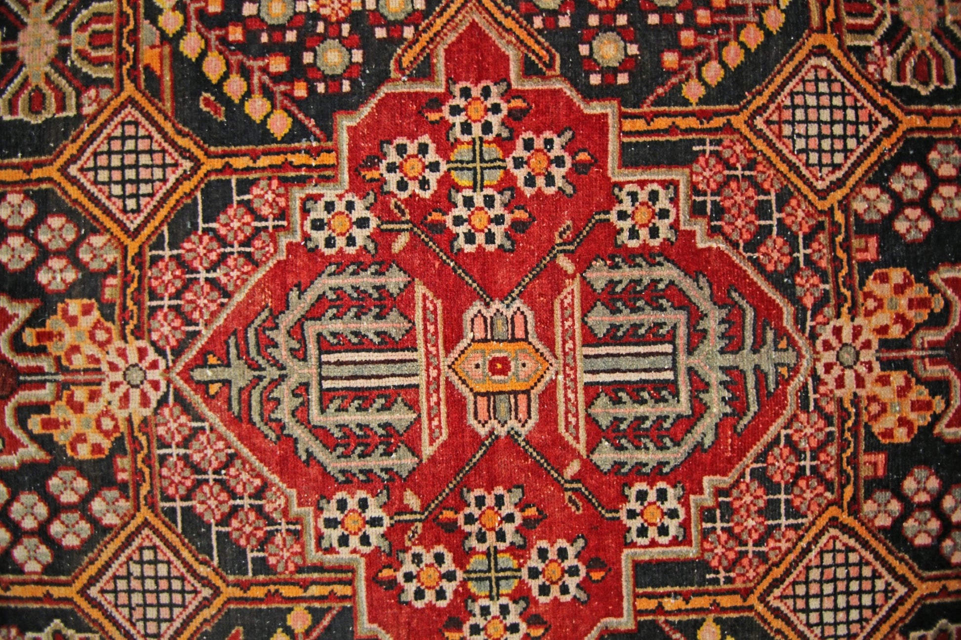 A vintage Persian Tabriz rug featuring a detailed geometric floral pattern in red and black.