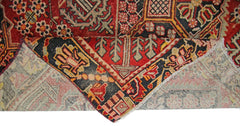 A vintage Persian Tabriz rug with a folded corner showing its intricate red and black pattern.