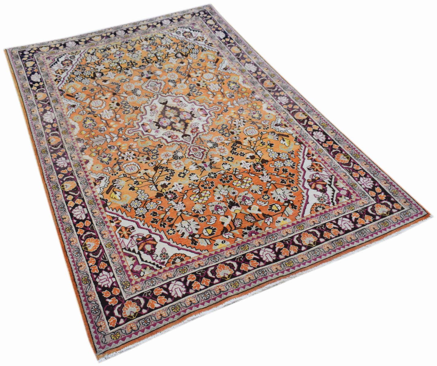 A vintage Persian Tabriz rug featuring an intricate floral pattern in orange and dark purple tones.