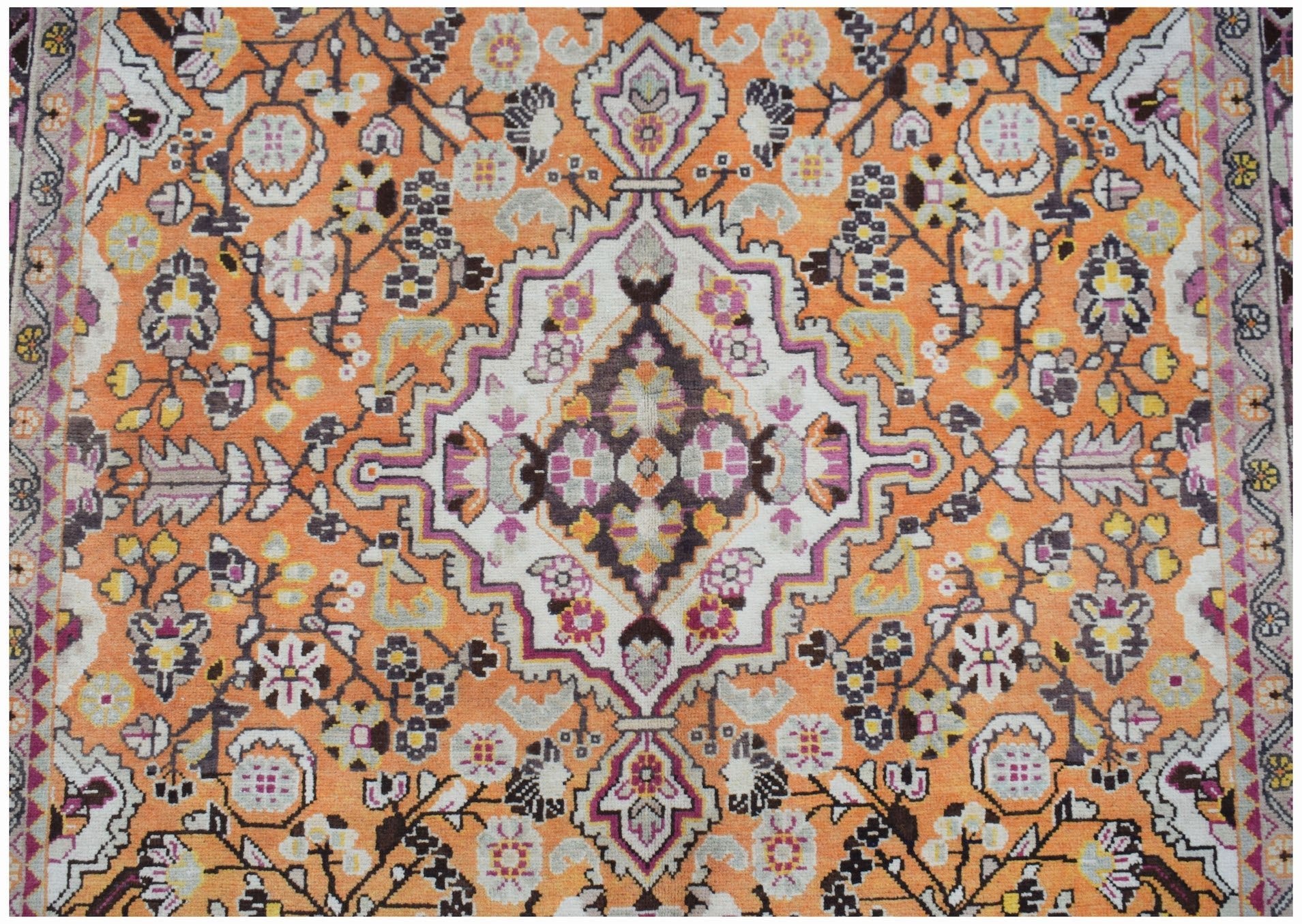 A vintage Persian Tabriz rug featuring a central medallion on an orange field with floral motifs.
