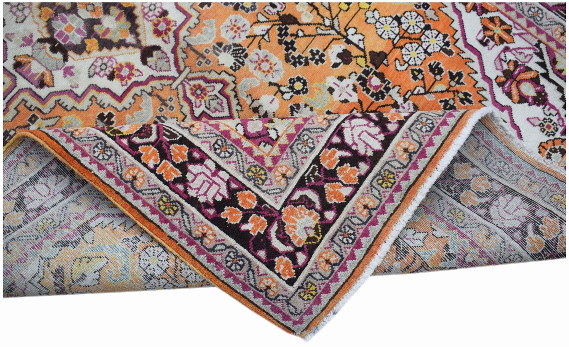 A vintage Persian Tabriz rug featuring an intricate floral pattern in orange, pink, and cream.