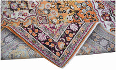 A vintage Persian Tabriz rug featuring an intricate floral pattern in orange, pink, and cream.
