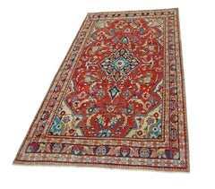 A vintage Persian Tabriz rug featuring a central floral medallion on a red field with ornate borders.