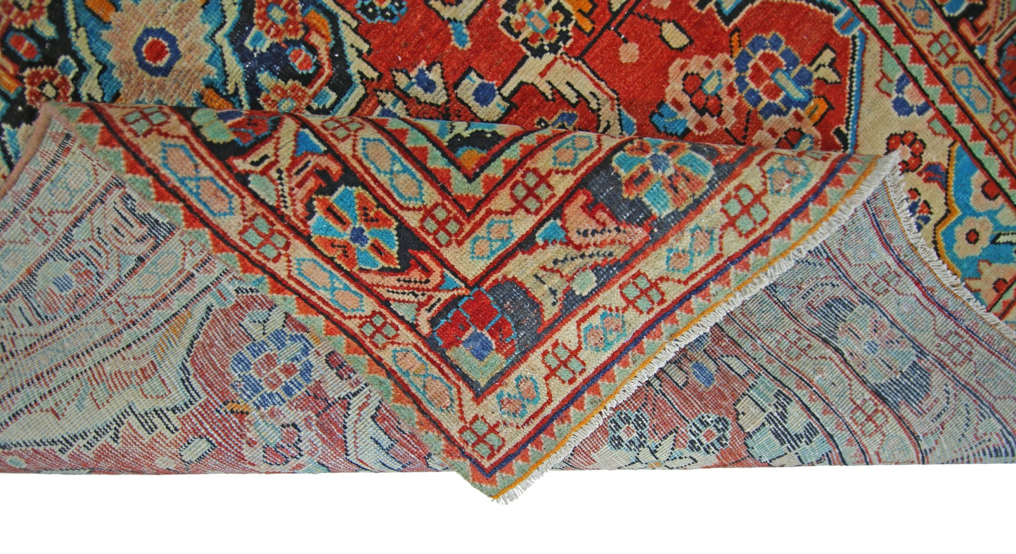 A vintage Persian Tabriz rug with a folded corner showing its intricate red and blue floral pattern.