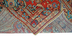 A vintage Persian Tabriz rug with a folded corner showing its intricate red and blue floral pattern.