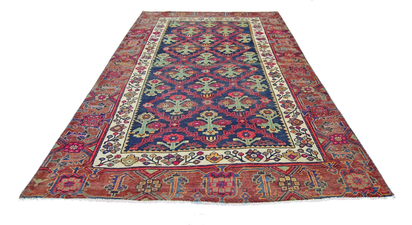 A vintage Persian Tabriz rug featuring a blue field with floral motifs and a red border.