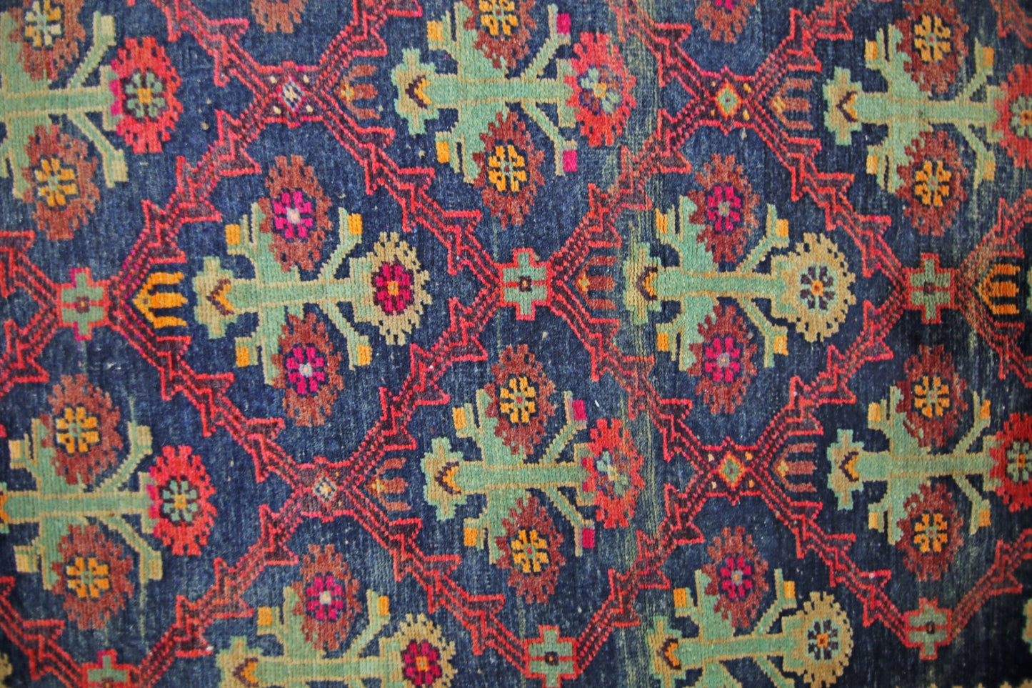 A vintage Persian Tabriz rug featuring a repeating geometric floral pattern in blue, red, and green.
