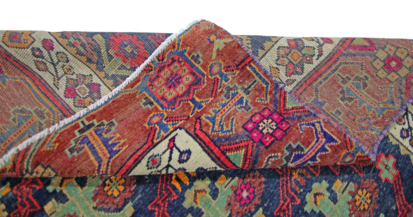 A folded vintage Persian Tabriz rug featuring intricate geometric patterns in red, blue, and green.