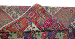 A folded vintage Persian Tabriz rug featuring intricate geometric patterns in red, blue, and green.